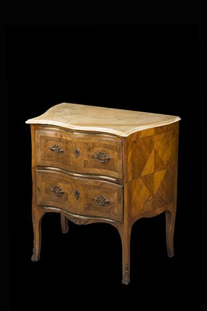 Comoncino di forma mossa lastronato in noce e filettato. Due cassetti sul...