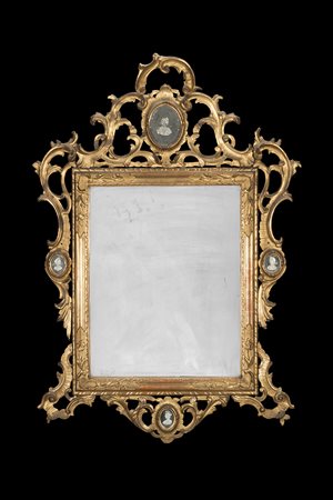 Specchiera in legno dorato e intagliato con fregi e cimasa decorati da...