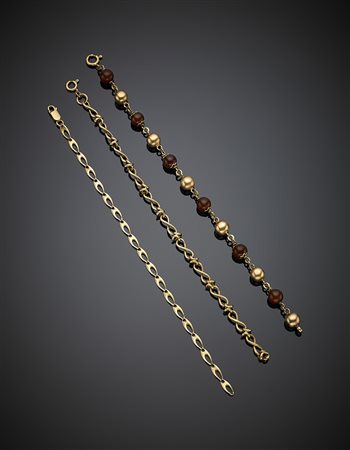 Tre bracciali a catena in oro giallo, uno con corniole e boules d'oro...