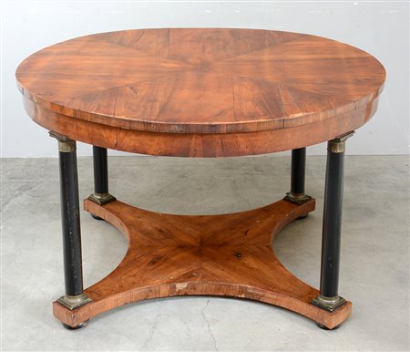 Tavolo "Impero" di forma tonda con piano e fascia lastronati in noce, gambe a...