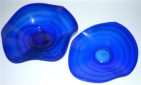 Lotto composto da due centrotavola a bordo sagomato in vetro blu decorato a...