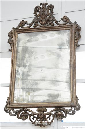 Specchiera in legno intagliato e dorato a mecca a volute, fiori e motivi...