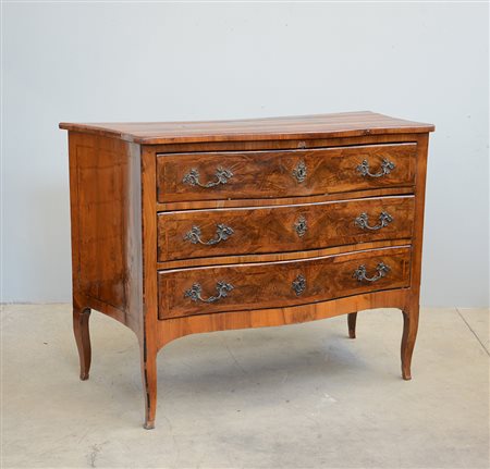 Comò di forma mossa lastronato in noce, radica di noce e filettato. Fronte a...