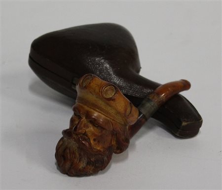 Pipa in schiuma scolpita a testa maschile con copricapo, bocchino in ambra....