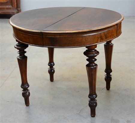 Tavolo tondo in noce, due cassetti nella fascia, quattro gambe sfaccettate...