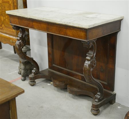 Console in noce con montanti intagliati poggianti su mensola, piano in marmo...