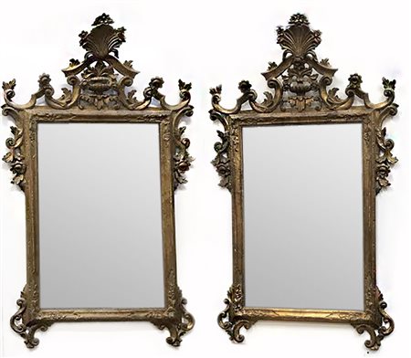 Coppia di specchiere in legno intagliato e dorato con cimasa e fregi...