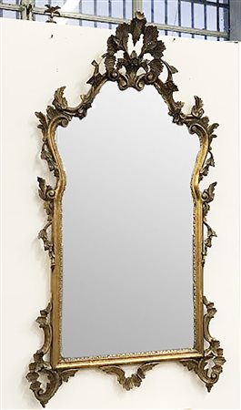 Specchio di forma sagomata in legno intagliato e dorato a volute (cm 135x64)...