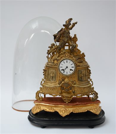 Pendola da camino in metallo dorato con cassa sormontata da moschettiere,...