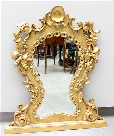 Caminiera di forma sagomata in legno dorato, intagliata a motivi vegetali,...