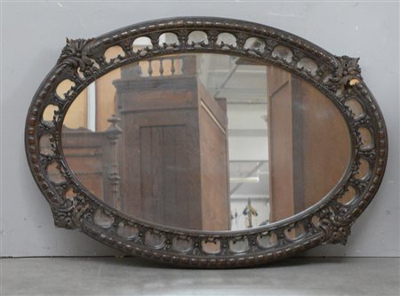 Specchiera ovale con cornice in legno intagliato e traforato a motivi...