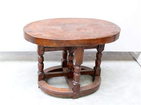 Tavolino in legno con piano ovale e cinque gambe tornite riunite da traverse...