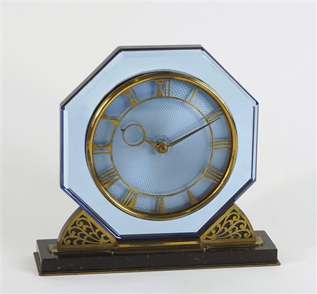Orologio da tavolo in vetro di forma ottagonale e base in legno. Lung. cm. 22.