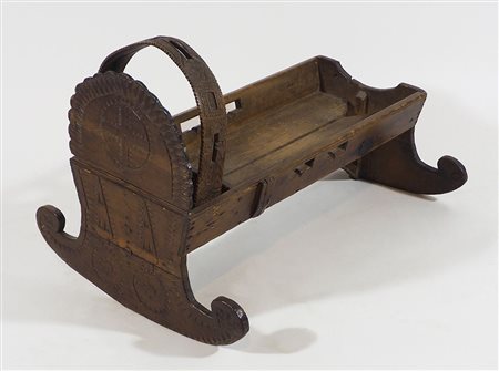 Antica culla basculante in legno finemente intagliato. Lung. cm. 77.