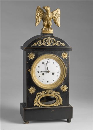 MANIFATTURA DEL XIX SECOLO Orologio da tavolo in legno ebanizzato, cimasa con...