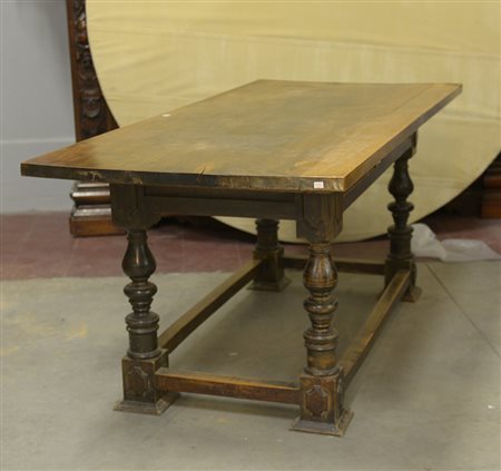 Tavolo in noce a due cassetti pannellati. Gambe tornite riunite da traverse...