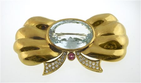 Spilla in oro giallo a forma di fiocco con diamantini e al centro topazio...