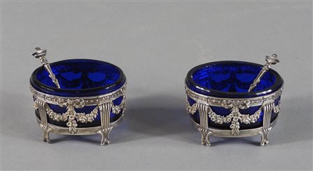 Paio di saliere in argento sbalzato di forma ovale con cucchiaini,...