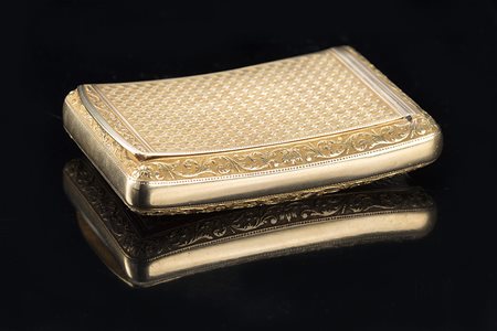 Tabacchiera di forma ricurva in oro cesellato sul bordo a volute fogliate e a...