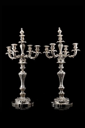 Coppia di candelabri in argento a cinque fiamme, braccia sagomate su colonna...