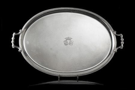 Vassoio biansato in argento con bordo a palmette, centrato da stemma Araldi,...