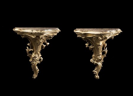 Coppia di mensole di forma sagomata in legno scolpito e dorato a volute e...