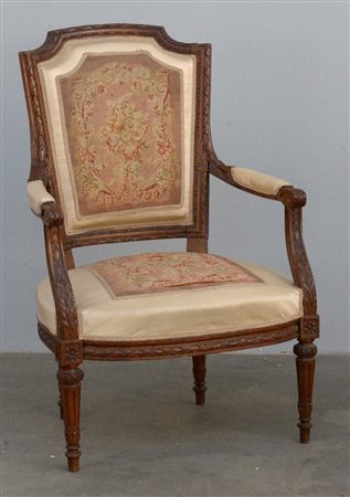 Poltrona in noce intagliato a decoro fogliaceo con seduta e dorsale centrate...