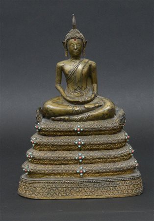 Scultura in bronzo raffigurante Buddha seduto su base a più livelli decorata...