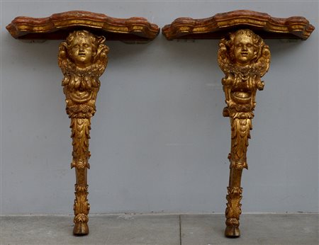 Coppia di console con sostegni in legno intagliato e dorato decorati da volti...