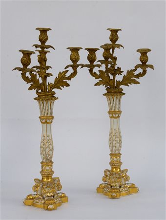 Coppia di candelieri tripodi in porcellana decorata in oro, parte superiore a...