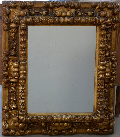 Specchiera con cornice in legno intagliato e dorato decorata da foglie e...