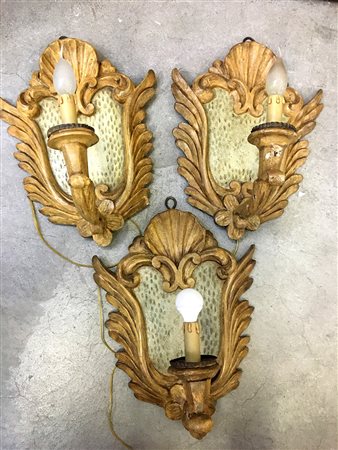 Gruppo di tre appliques ad una fiamma in legno laccato e intagliato a foglie,...