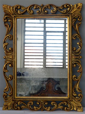 Specchiera con cornice traforata a motivi fogliacei in legno intagliato e...