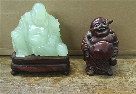 Due sculture in pietra dura raffiguranti Buddha, uno con base in legno...