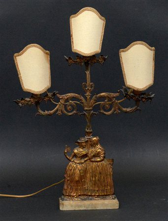 Candelabro in bronzo a tre fiamme decorato con figure femminili, volute e...