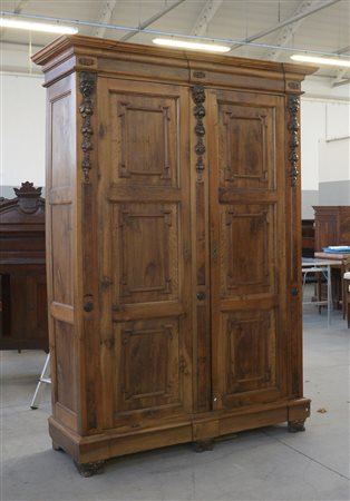 Armadio a due ante riquadrate, montanti decorati da fregi scolpiti con...