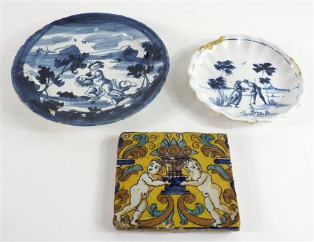 Lotto in maiolica a smalti policromi composto da due piatti e piastra. Misure...