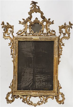 Grande specchiera in legno dorato con cimasa e fianchi finemente scolpiti....