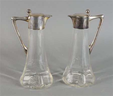Coppia di brocce in cristallo con manico, collo e tappo in argento. Austria,...