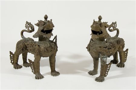 Coppia di sculture in bronzo a patina marrone raffiguranti cani orientali....