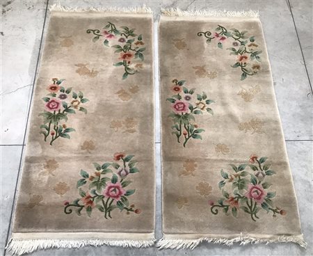 Coppia di scendiletto su fondo beige decorati in policromia a motivi floreali...