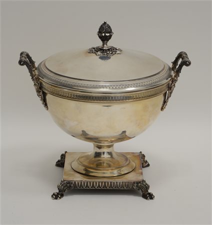 Coppa biansata in argento poggiante su base quadrata sorretta da piedi ferini.