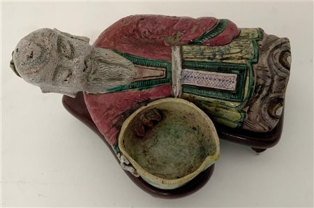 Scultura raffigurante dignitario sdraiato con coppetta in ceramica a smalti pol