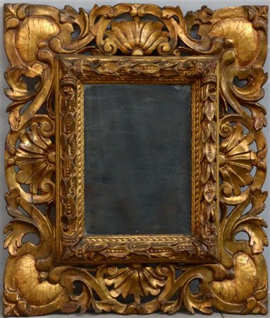 Specchiera con cornice in legno intagliato e dorato decorata da foglie e volute