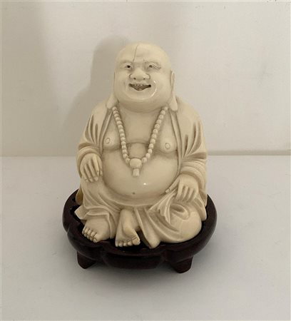 Scultura raffigurante Buddha seduto in avorio, base in legno (h. cm 11) 
Cina,