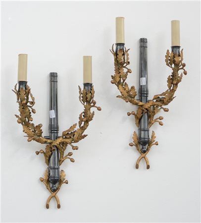 Coppia di appliques a due fiamme con montanti decorati a mezzo cannone in metal