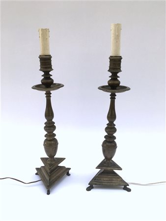 Coppia di porta ceri in bronzo con fusto tornito su base tripode, montati a luc