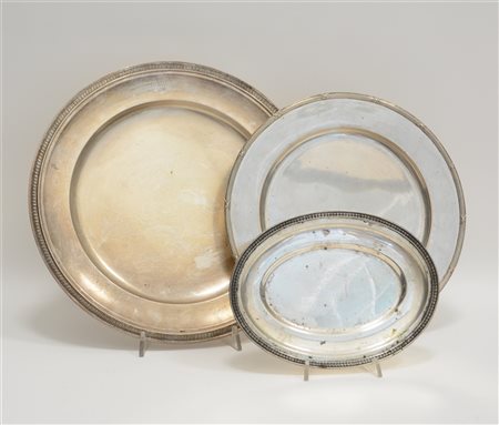 Lotto di tre vassoi in argento, due tondi e uno ovale con bordi cesellati a "pa