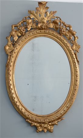 Specchio di forma ovale con cimasa intagliata, traforata e dorata a vite e pamp