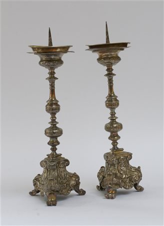 Coppia di portaceri in metallo argentato e sbalzato a volute e foglie. Secolo X